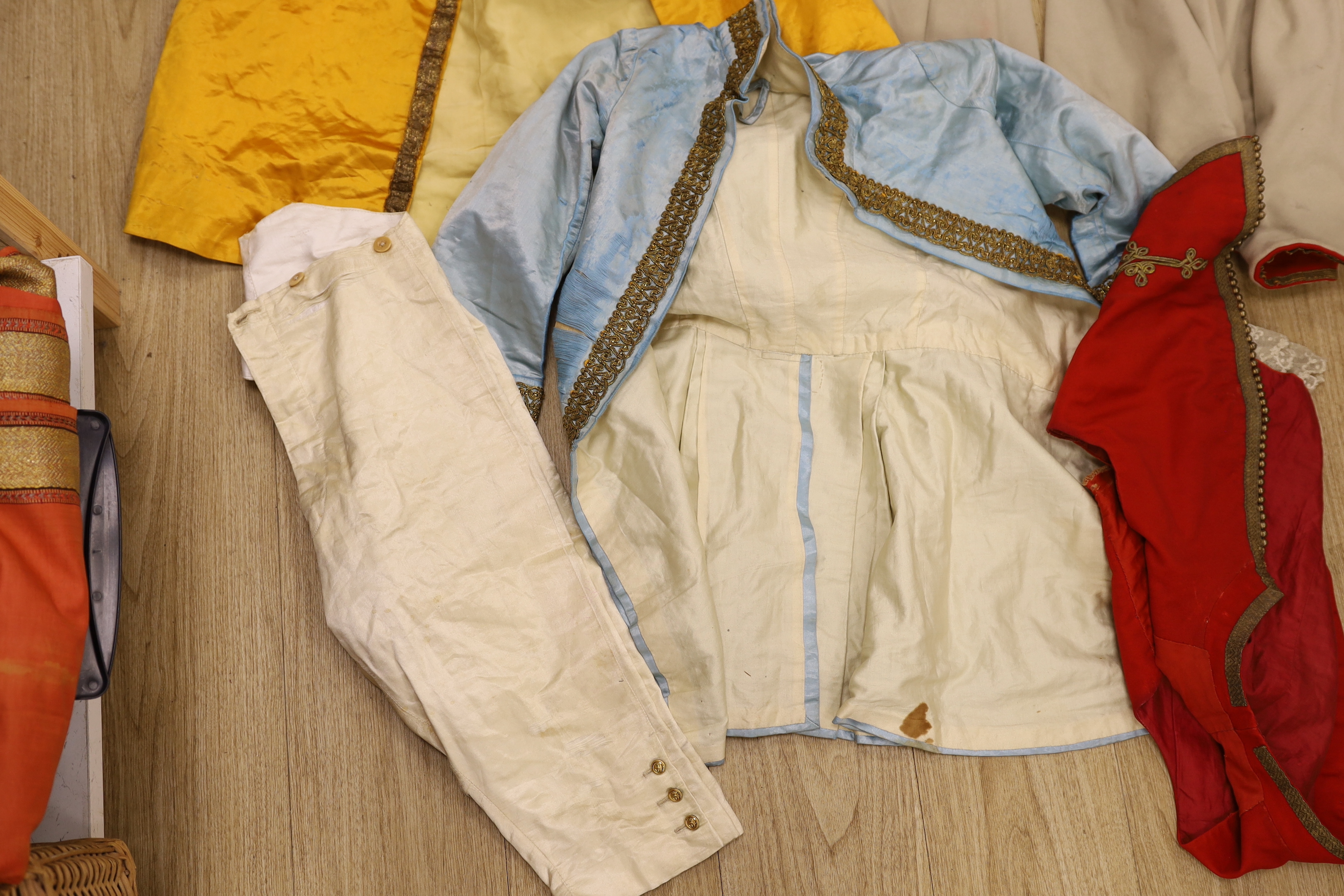 A red wool and gold braided gentleman's jacket with waistcoat, possibly originally military with later alterations, a similar blue satin jacket, etc.